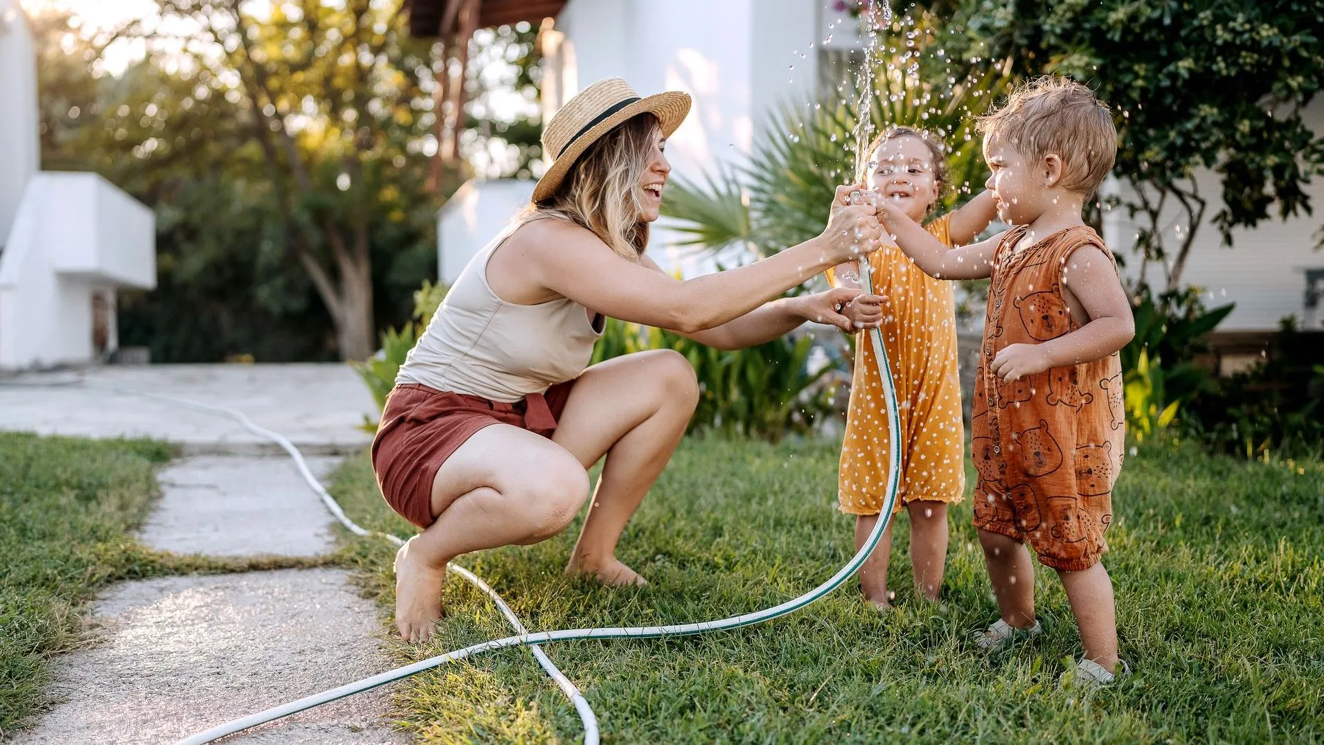 Mom playing with kids in yard.